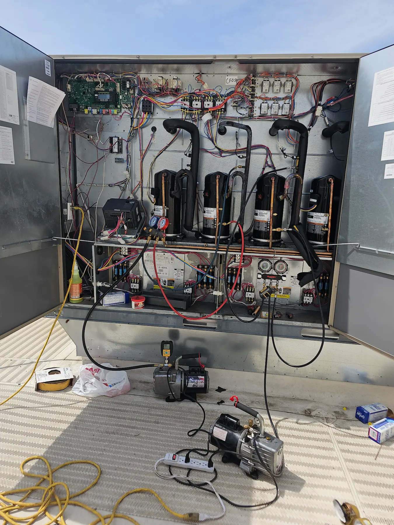 Open HVAC unit with electrical components and tools on the ground. Expert repairs and maintenance for reliable operation.